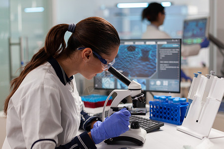 抗病毒治疗具有保护眼镜研究样本的科学家 通过显微镜进行抽样研究药品治疗技术化学家展示电脑实验室制药实验微生物学背景
