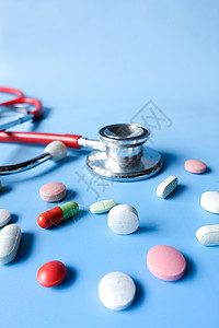 蓝色背景的彩色医用药丸和听诊器背景图片