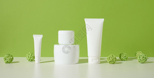 罐子 白色桌子上的化妆品空白色塑料管 绿色背景 用于奶油 凝胶 血清 广告和产品促销的包装背景图片
