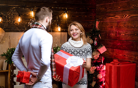 圣诞节晚会英俊的男人带着礼物盒给女朋友惊喜 男人时髦送礼物给女孩圣诞装饰品背景 给甜心的惊喜 圣诞快乐和新年快乐 圣诞礼物背景