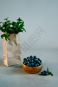 蓝莓包一个小木碗 有浆果 和香味薄荷的枝子分支机构食物森林盘子营养蓝色工艺叶子甜点牛皮背景