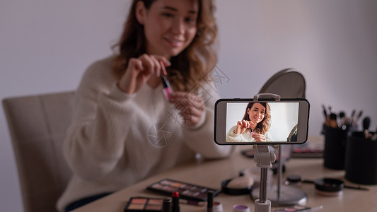 Caucasian年轻女性正在她的手机上录制一个在线化妆培训录像 视频博客女孩会化妝背景图片