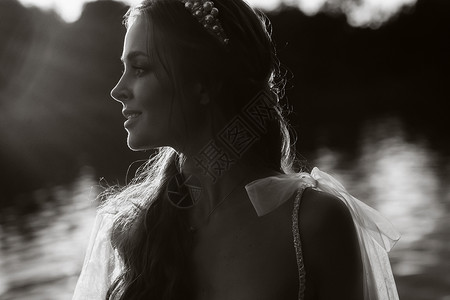 穿着白色礼服的优雅新娘在日落时享受自然 在公园里 身着彩礼服的模范黑白照片若虫山河裙子手套花束自由旅行幸福婚礼背景图片