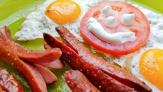 油炸鸡蛋馍皮烤鸡蛋和香肠的顶端景色 在绿色盘子上 为婴儿提供早餐鸡蛋食物家庭想像力油炸微笑蔬菜美食孩子厨房背景