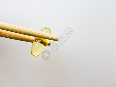 鱼油胶囊用中国筷子 在白色背景上的欧米茄 3 高分辨率产品 食物供给 健康生活方式的维生素 脂肪酸 体内新陈代谢处方愈合宏观团体背景图片