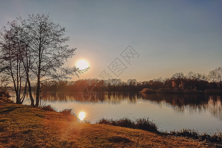 水太阳树素材生动的秋天日落 日落秋天风景在河的与光亮的草在岸上 明亮的夜晚风景秀丽 天空五彩缤纷晴天场景蓝色季节日出森林反射阳光地平线公园背景