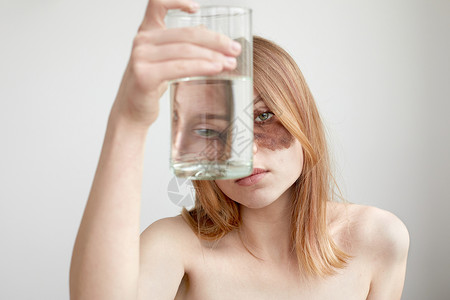 拿着玻璃杯水的带面膜的妇女高清图片