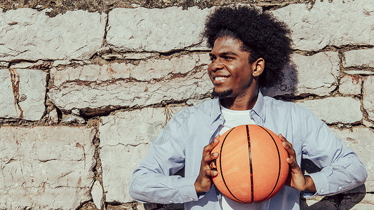 1号篮球素材在石墙上带篮子球的 年轻Afro男子 复制空间背景