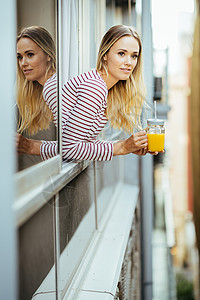年轻女子喝着一杯天然橙汁 从家窗外倾斜而下 从家里走出来黑发水果成人快乐食物口渴果汁稻草玻璃橙子美丽高清图片素材