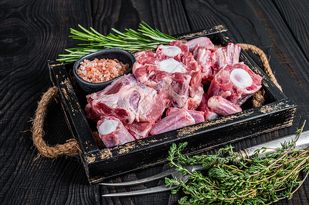 木托盘中的生小牛肉牛肉牛尾肉与百里香 黑色的木制背景 顶视图炙烤红色烹饪木板牛扒羊肉桌子尾巴屠夫奶牛背景图片