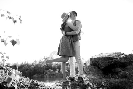 石头带爱素材一对年轻夫妇 一个男人和一个女孩走在 环绕着山湖的附近背景多云套装稻草褐色蓝色棕色夫妻裙子花岗岩背景