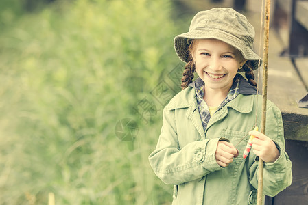 坐着钓鱼的女孩小女孩笑着微笑的小鱼女孩女士帽子浮标乐趣孩子童年青年娱乐池塘女性背景