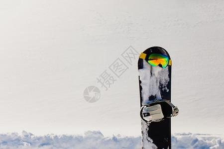 滑雪板和滑雪谷歌 在自由斜坡附近的雪上躺下蓝色阳光踪迹季节活动乐趣高山运动旅行反射背景图片