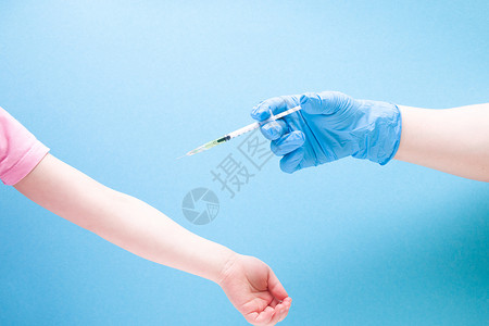 蓝色橡胶医用手套中的女性手在蓝色背景复制空间 治疗和保健概念 儿童糖尿病概念上用胰岛素注射器给小女孩注射背景图片