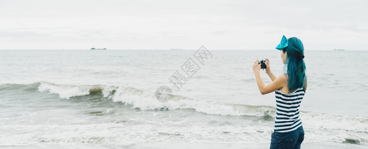 蓝色头发女孩旅游女游客拍摄海景照片背景
