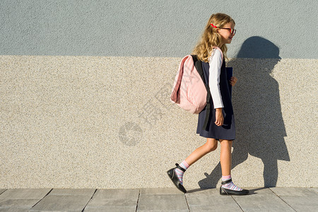 我上学了他手里拿着笔记本的小学女学生 一个背着背包的女孩去上学 回到学校背景