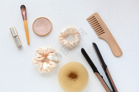 木发刷 直发器和黄色丝绸 Scrunchy 隔离在白色 平躺美发工具和配件 如彩色发带 弹性发带 发带发夹梳子剪刀团体造型沙龙配背景图片