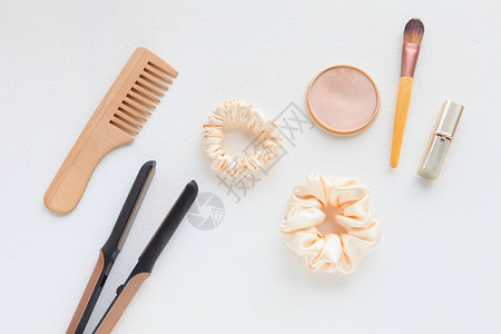 木发刷 直发器和黄色丝绸 Scrunchy 隔离在白色 平躺美发工具和配件 如彩色发带 弹性发带 发带发夹团体卷发器理发梳子配饰背景图片