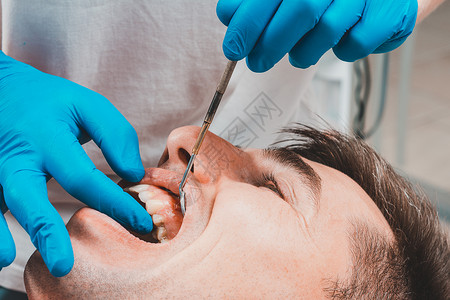 拜访牙医时 牙医会评估口腔并确定牙齿的问题区域 瘘口 2021卫生保健搪瓷无菌器械唾液检查牙龈镜子从业者治疗背景图片