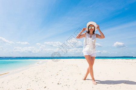 桑给巴尔在海滩上戴着帽子的美丽笑脸女孩旅行女士享受女性头发闲暇太阳海洋裙子天空背景