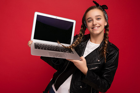 照片中美丽的年轻女孩拿着电脑笔记本电脑 看着因背景多彩而孤立的相机屏幕电子神器监视器空间互联网技术广告小样背景图片