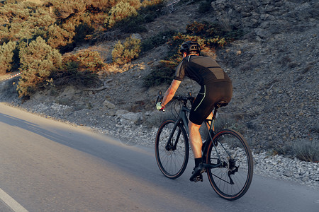 壮观骑士日出时在山路上的职业职业骑手竞赛男人自行车成人头盔旅行骑士运动速度运动员背景