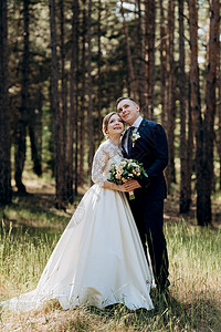 新娘和新郎在松树林中行走棕色绿色森林射线花束公园分支机构婚礼花朵男朋友背景图片
