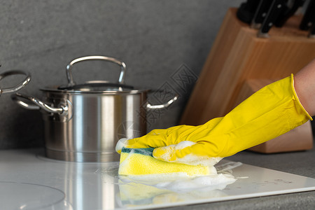 女性手握黄色手套 用海绵清洗电炉灶抹布灰尘家务家庭工作清洁工卫生服务溅射乳胶背景图片