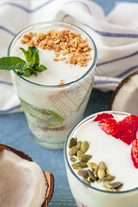 格拉迈格加酸奶和浆果的格拉诺拉 用来在桌上吃健康早餐燕麦杏仁奶油饮食麦片奶制品食物蜂蜜坚果玻璃背景