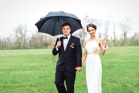 新娘和新郎在雨季的结婚日散步微笑下雨裙子绿色白色女孩喜悦婚礼新婚黑色背景图片