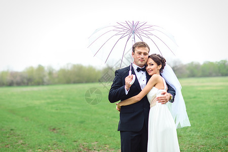 新娘和新郎在雨季的结婚日散步裙子微笑喜悦婚礼夫妇天气白色新婚女孩下雨背景图片