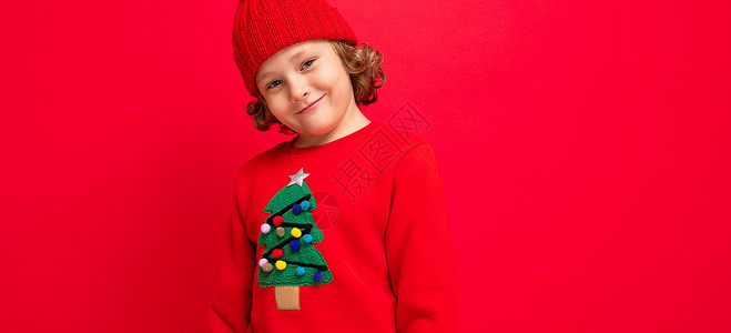 有卷卷卷卷的酷男孩 红色背景 穿着毛衣和圣诞树新年情绪行动卷发销售背景图片