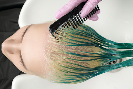 淋浴时梳理顾客长绿色和变色头发 同时洗发水的毛发设计师最顶端风景背景图片