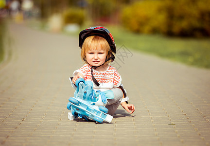 穿着溜冰鞋和头盔的2岁女孩享受婴儿活动幸福安全溜冰者滚筒公园孩子闲暇背景图片