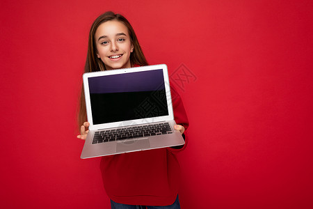 照片中美丽的年轻女孩拿着电脑笔记本电脑 看着因背景多彩而孤立的相机互联网电子神器技术屏幕小样监视器空间背景图片