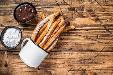 巧克力天天圈带糖和巧克力酱的Churros 木制背景 顶视图 复制空间食物甜点棕色白色油条黑色肉桂美食小吃糕点背景