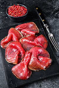 黑色砧板Bresaola治愈了肉牛肉切片 意大利安提帕斯蒂 黑色背景乡村火腿食物烹饪拼盘牛肉小吃红色木板熏制背景