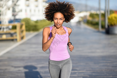 爆炸动机黑人女人 衣冠楚楚的发型 在城市路上户外跑女性福利运动装头发街道城市运动跑步赛跑者闲暇背景