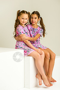 两个小女孩在演播室 摆着白色立方体青春期快乐工作室乐趣裙子孩子女孩衣服家庭童年背景图片