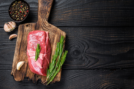 大理石纹肉木制切木板上新鲜鲜生小牛肉牛排 黑木背景 顶视图 复制空间背景