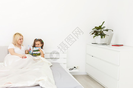 母亲和女儿在床上看一本照片书女性卧室专辑房间房子女孩邻家照片回忆枕头背景图片