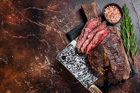 Onglet 切肉牛排 在屠宰板上用刀砍头 深底背景 顶视图 复制空间背景