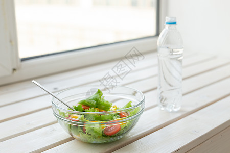 蔬菜水白色窗台上放着蔬菜沙拉和一瓶水 健康生活方式体育活动和适当营养的概念背景