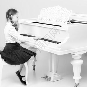 弹钢琴的女孩黑色音乐学校的一个女孩弹钢琴的婴儿红色童年键盘夫妻孩子乐器喜悦白色女孩背景