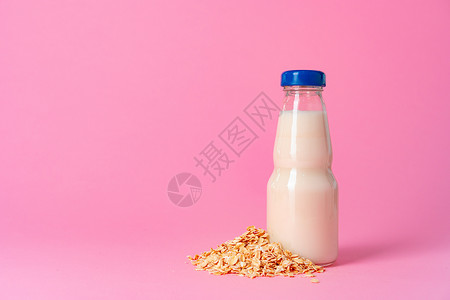 粉红底的玻璃件和干燕麦片中的煤奶婴儿产品液体护理食物瓶子桌子粉色玻璃商品背景图片