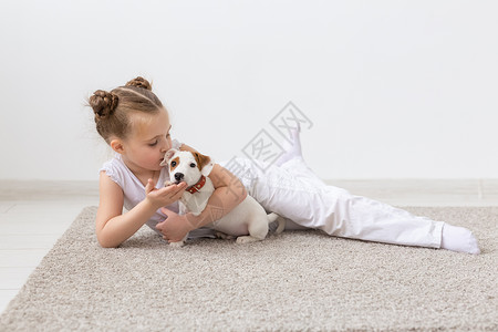 地板狗童年 宠物和狗概念     小女孩与小狗在地板上摆布黑发犬类友谊说谎幸福动物猎犬袜子乐趣地面背景