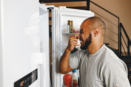 非裔美国人因为冰箱的臭味而关上鼻闭鼻子家庭贮存男性产品器具成人食物男人厨房背景图片