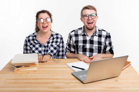 人与教育概念两名身着格格衬衫的学生坐在一张桌子上电脑快乐男性笔记本斗争图书工作室享受眼镜喜悦背景图片