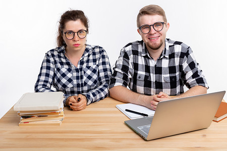 人与教育概念两名身着格格衬衫的学生坐在一张桌子上眼镜图书笔记本喜悦极客斗争成人男人享受女士背景图片