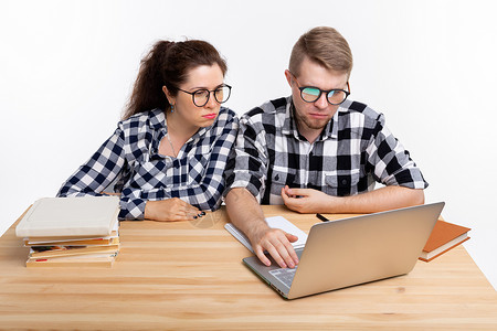 人与教育概念两名穿着格格衬衫坐在桌边的令人迷惑的学生女孩图书快乐成人享受斗争电脑逗乐笔记本夫妻背景图片